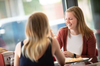 Two women laughing over lunch, for a guide to ADHD specialists in Austin